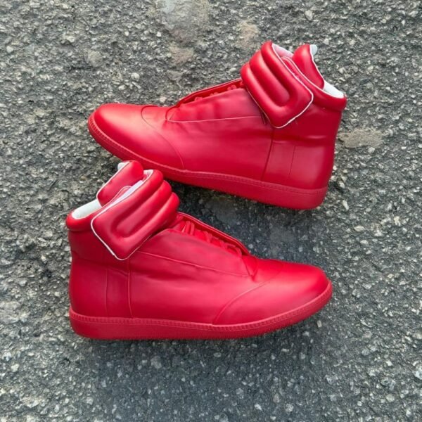 These Maison Margiela Future high top sneakers feature a vibrant red finish with a signature thick padded ankle strap and a sleek structured silhouette. The bold color and distinctive ankle detailing create a striking and contemporary appearance.